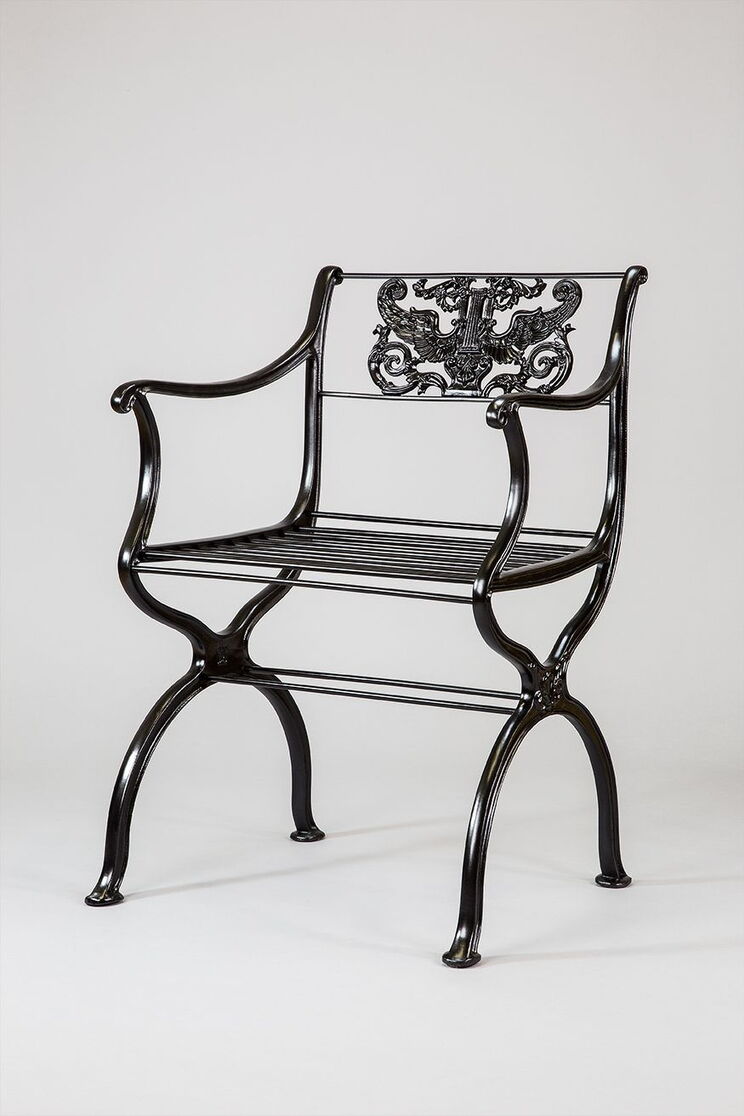 Cast-iron garden armchair with curved armrests and an openwork backrest featuring an eagle motif
